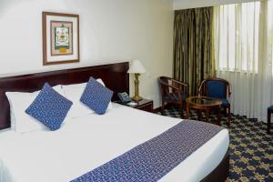 a hotel room with a large bed with blue pillows at Jacaranda Hotel Nairobi in Nairobi