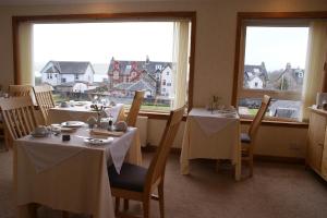 a dining room with two tables and two windows at Greencourt Guest House in Oban