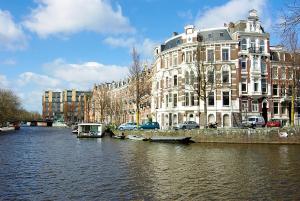 een rivier met gebouwen en auto's naast een gebouw bij Luxury Leidseplein with Private Patio in Amsterdam