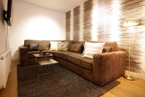 a living room with a brown couch and a table at Luxury Leidseplein with Private Patio in Amsterdam