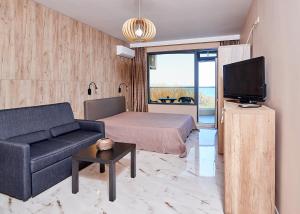 ein Wohnzimmer mit einem Sofa, einem Bett und einem TV in der Unterkunft Apartments Magic in Pomorie