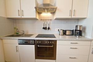 cocina con armarios blancos, fogones y fregadero en Ferienwohnung Babelsberg en Potsdam