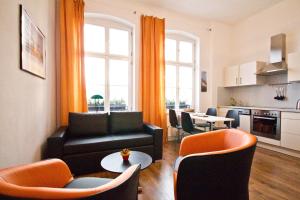 sala de estar con sofá negro y sillas de color naranja en Ferienwohnung Babelsberg en Potsdam