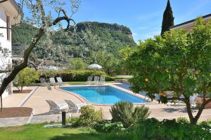a swimming pool with chairs and a mountain in the background at Cà Gardesana With Pool in Garda