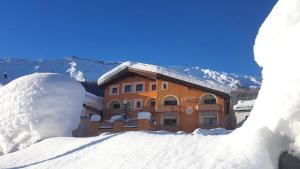 a building in the snow with a pile of snow at Hotel Landgasthof Staila in Fuldera