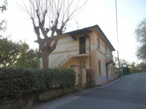 a house with a tree on the side of a street at Appartamento nel Verde in Pietrasanta