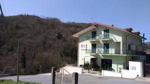 um edifício branco com uma varanda numa colina em Palia's Hotel em Laino Borgo