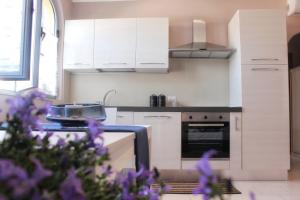 a kitchen with white cabinets and purple flowers in the foreground at Villa Carina in Massa +1 photo
