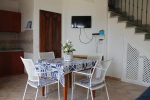 a dining room with a table with chairs and a tv at Villa Le Conchiglie in Nebida