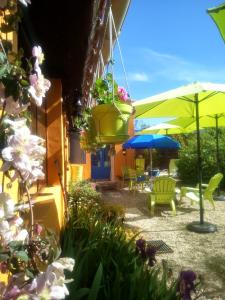 eine Terrasse mit Stühlen, Sonnenschirmen und Blumen in der Unterkunft La Joliette in Junas