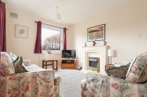 a living room with two chairs and a fireplace at Silver Lining - Orchard House with balcony in Edinburgh