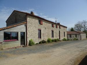 a stone house on a dirt road next to a street at La Lauriére in Treize-Vents