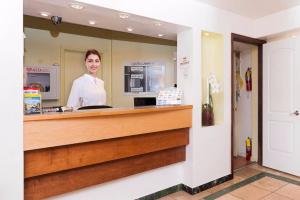 a woman is standing behind the counter of a pharmacy at Gables Inn in Miami