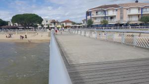 a boardwalk leading to a beach with people on it at Résidence Casino in Andernos-les-Bains