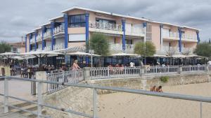 a building on the beach with people sitting on the sand at Résidence Casino in Andernos-les-Bains