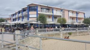 un edificio en la playa con gente sentada en la arena en Résidence Casino, en Andernos-les-Bains