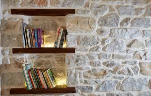 two wooden shelves with books on a stone wall at Villa Thea in Makrirrákhi