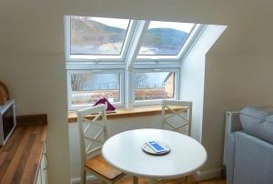 een kleine kamer met een tafel en twee ramen bij Urquhart Bay Croft in Drumnadrochit