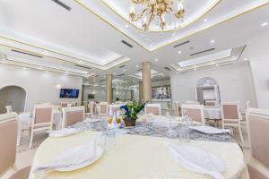 een grote kamer met een tafel met witte stoelen en een kroonluchter bij Hotel Belagrita in Berat