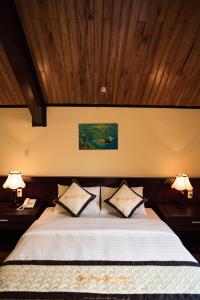a bedroom with a bed with two nightstands and two lamps at Spring Garden Villa in Hue