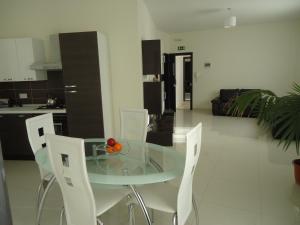 a glass table and white chairs in a kitchen at Shamrock Flats in Mellieħa