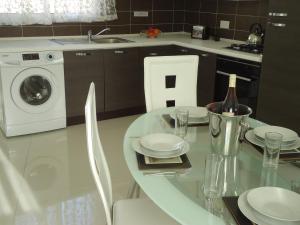 a kitchen with a glass table and a washing machine at Shamrock Flats in Mellieħa