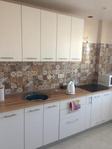 a kitchen with white cabinets and a sink at Apartment on 2-Y Khlynovskiy Pereulok 1 in Kirov