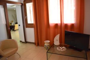 un soggiorno con TV, sedia e tavolo di Hotel Il Portico a Favignana