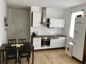 a kitchen with white cabinets and a table and a dining room at Ferienwohnung Villa Seeblick in Bodensdorf