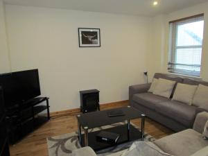 a living room with a couch and a tv at Farraline Court in Inverness
