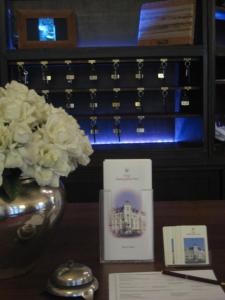 Hotel Markgräfler Hof في كارلسروه: طاولة مع إناء من الزهور البيضاء وبطاقة