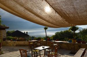 a patio with tables and chairs under a large umbrella at Anemi in Káto Pediná
