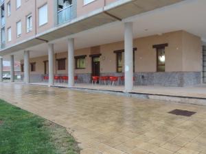 a building with white columns and red tables and chairs at Albergue Santo Tomás de Canterbury in León