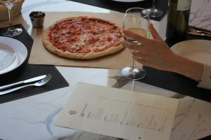a person holding a glass of wine next to a pizza at Evripides Hotel in Athens