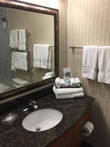 a bathroom with a sink, mirror and a towel rack at Best Western Plus Kelowna Hotel & Suites in Kelowna