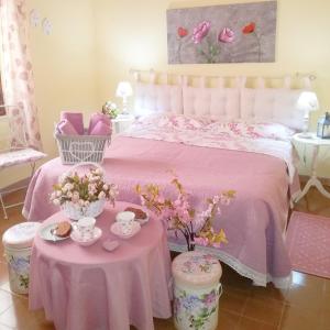 a bedroom with a pink bed and two tables with flowers at B&b il Giardino da Pina in Tuili