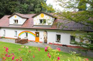 a white house with a rainbow in the yard at Märchenhotel Waldpension Nebelstein in Harbach
