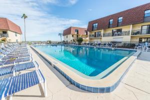a swimming pool at a resort with chairs and a building at Cocoa Beach Club in Cocoa Beach
