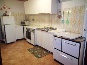菲耶拉迪普里米耶羅的住宿－da Michela，厨房配有白色橱柜、水槽和冰箱。