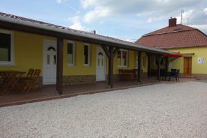 ein gelbes Haus mit Tischen und Stühlen davor in der Unterkunft La Familia in Štúrovo