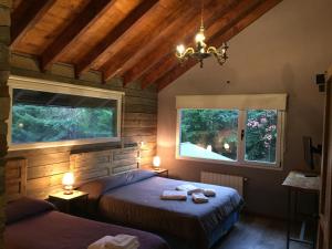 1 dormitorio con 2 camas y 2 ventanas en Hostería Las Cumbres en Villa La Angostura