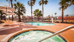 a swimming pool with palm trees in a resort at Best Western Beachside Inn in South Padre Island