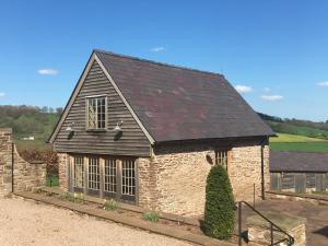 uma pequena casa de pedra com um telhado preto em Demesne Farm Guesthouse em Monmouth