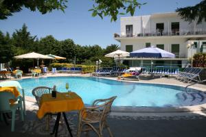 a swimming pool with a table and chairs and a building at Hotel Carmencita in Anacapri