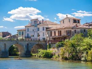a bridge over a river in a town with buildings at La Joliette in Junas