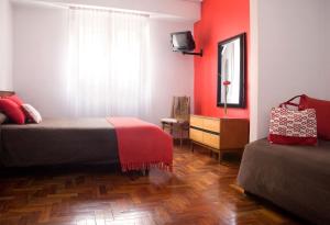a bedroom with two beds with red walls and a window at Petit Recoleta Suites in Buenos Aires +38 photos