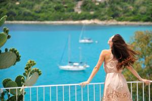 a woman standing on a fence looking at the water at Arbatax Park Resort - Suites Del Mare in Àrbatax