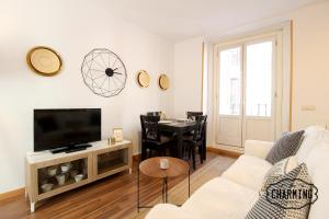 a living room with a couch and a tv and a table at Huertas Apartment - Estancias temporales in Madrid