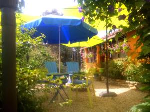 eine Terrasse mit einem blauen Sonnenschirm und Stühlen in der Unterkunft La Joliette in Junas
