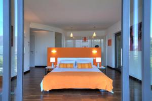 ein Schlafzimmer mit einem großen Bett mit einer orangefarbenen Decke in der Unterkunft Sant’Andrea Penthouse in Menaggio